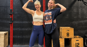 Mother and daughter flexing their biceps together in front of a squat rack at City Fit Shop in Edmonton