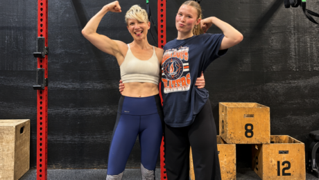 Mother and daughter flexing their biceps together in front of a squat rack at City Fit Shop in Edmonton