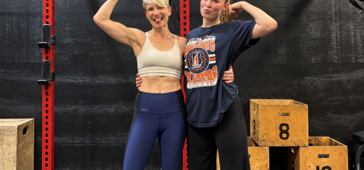 Mother and daughter flexing their biceps together in front of a squat rack at City Fit Shop in Edmonton